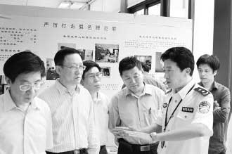 圖為公安部經偵局副局長高峰(右)向公安部特邀監督員們介紹“亮劍”行動展覽情況。 